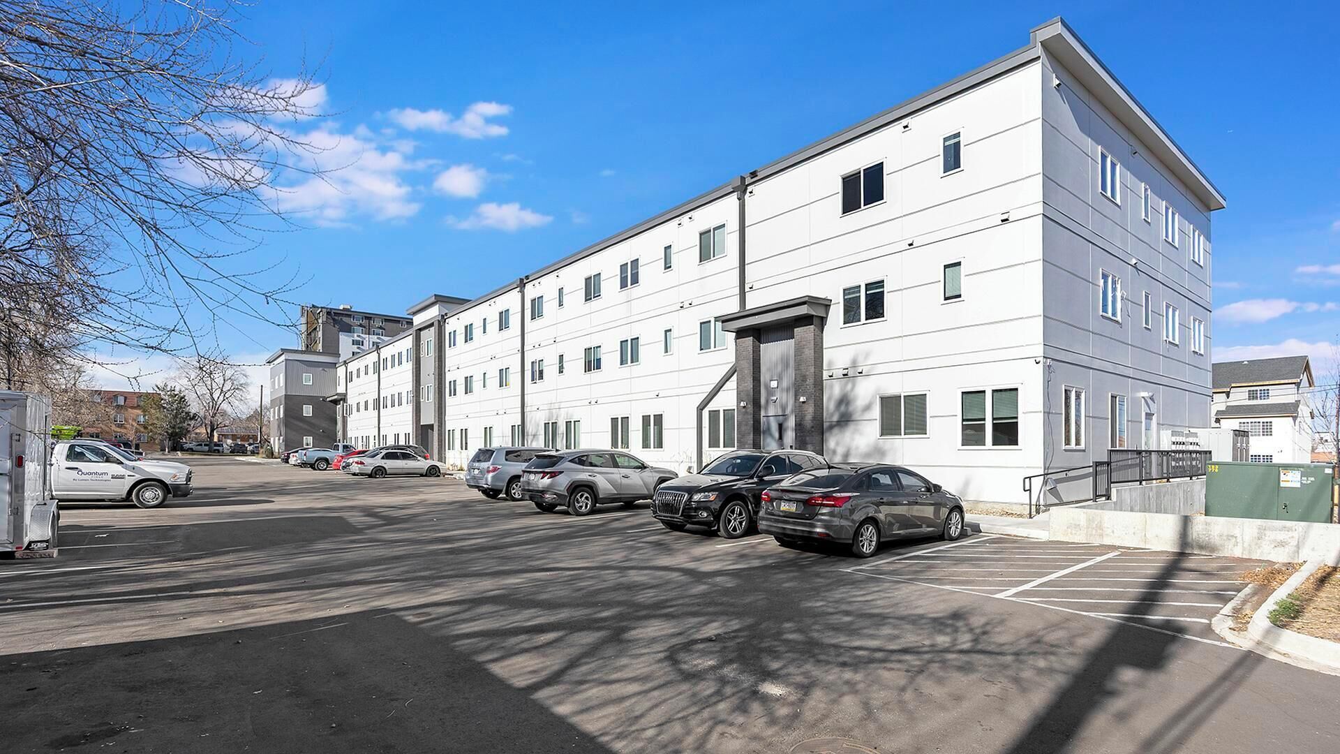 A multi-story building with a parking lot in front.