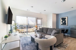 Ein modernes Wohnzimmer mit Sofa, Couchtisch, Fernseher und einem Balkon mit Blick.