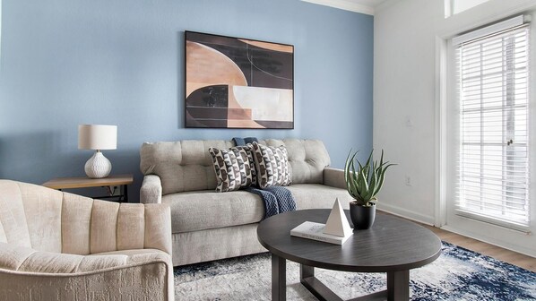 A living room with a sofa, armchair, coffee table, and a painting on the wall. - Landing | Beautiful 1BD, Clubhouse (Jacksonville)