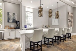 A modern kitchen with a central island, bar stools, pendant lighting, and a view of the outside. - Landing | Beautiful 1BD, Clubhouse (Jacksonville)