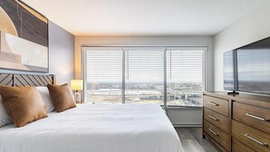 Quarto de hotel moderno com uma cama grande, TV e vista para a cidade.