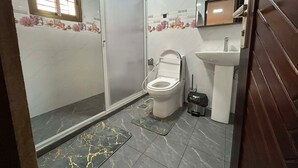 Une salle de bain avec des toilettes, un lavabo et une douche.