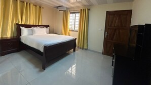 A hotel room with a bed, curtains, a wardrobe, and a television.