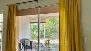 Una habitación con puerta de vidrio corrediza, alfombra estampada y una silla.