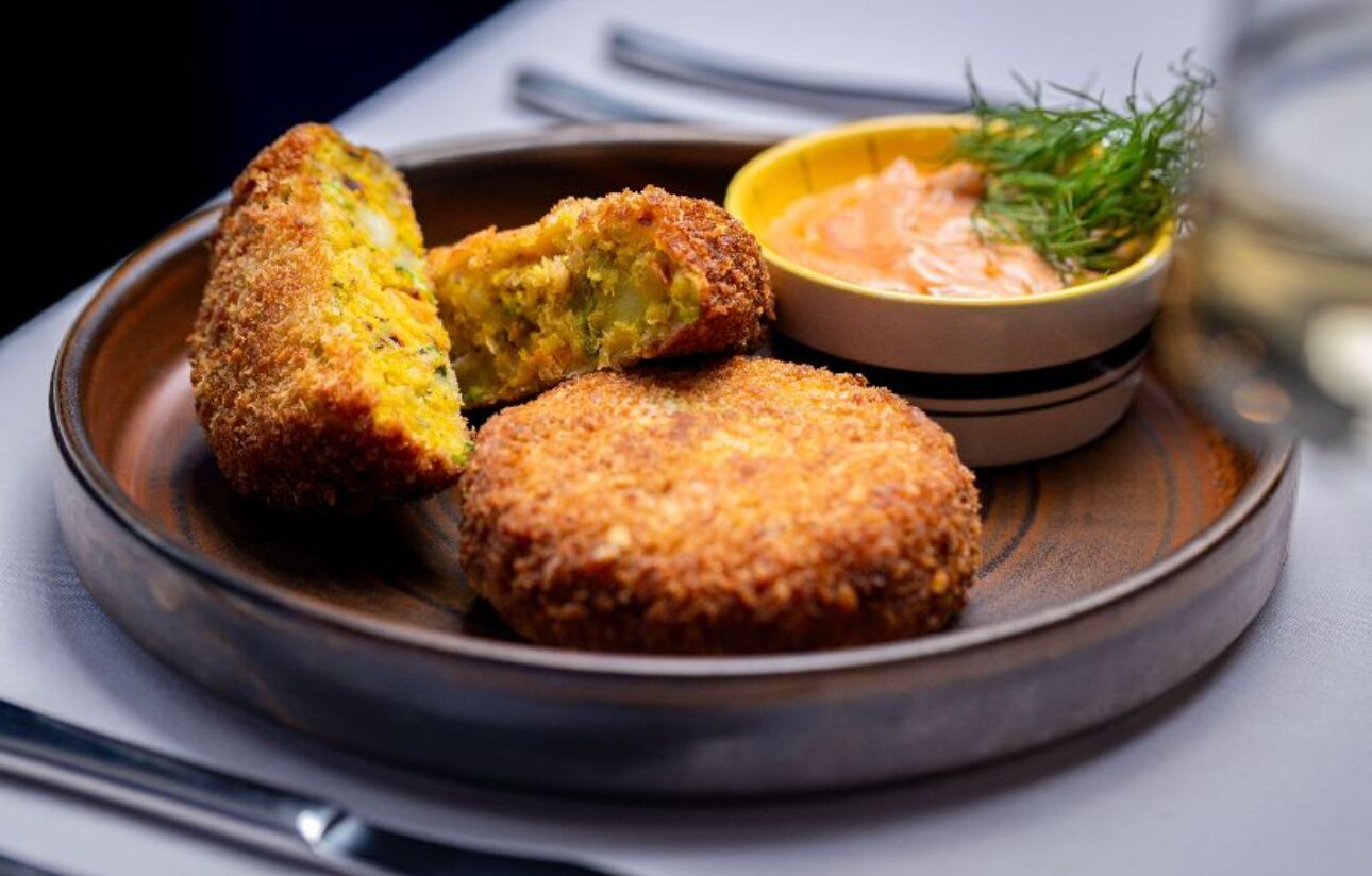A plate with three breaded items and a bowl of sauce.