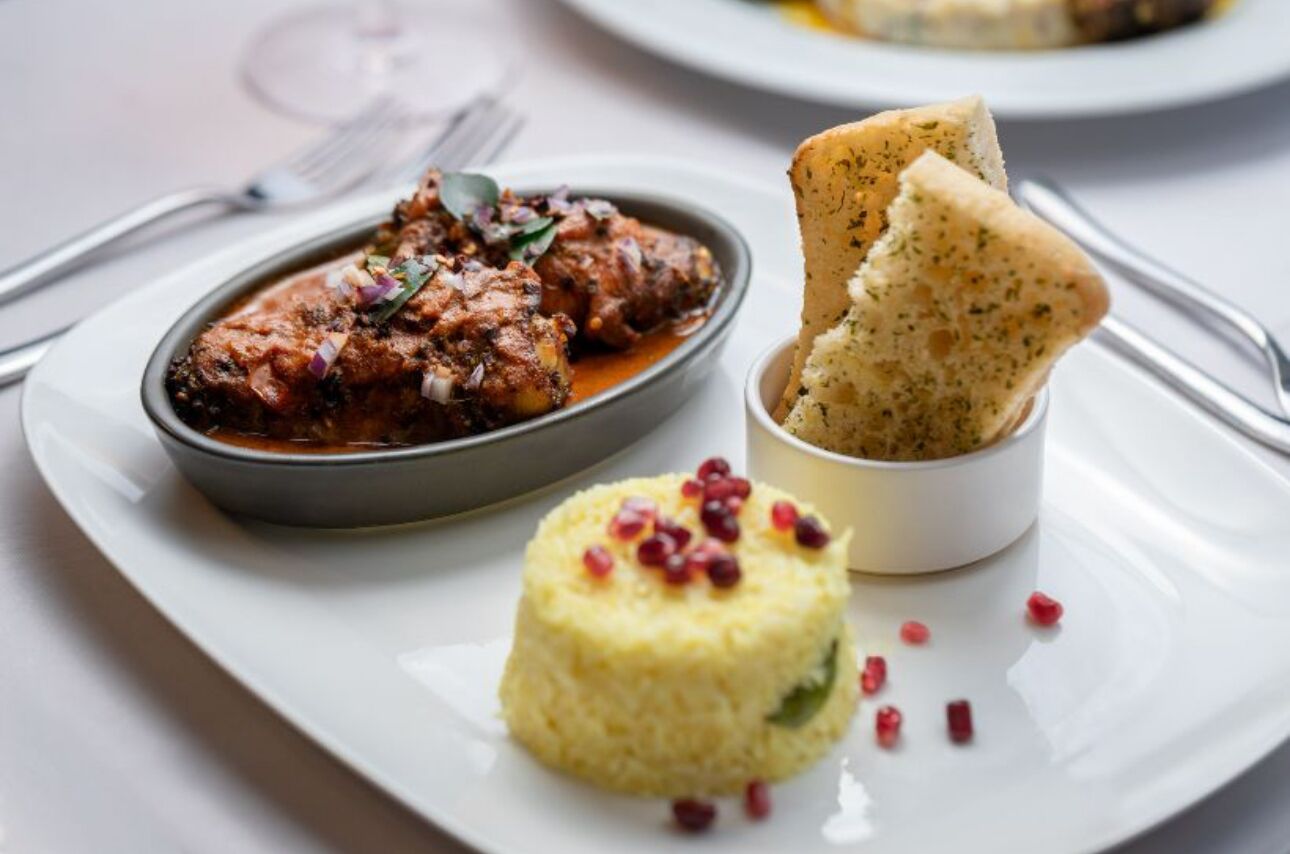 Un plato con carne, un cuenco pequeño de arroz y una rebanada de pan.