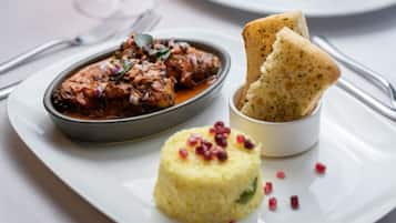 Un plato con carne, un cuenco pequeño de arroz y una rebanada de pan.