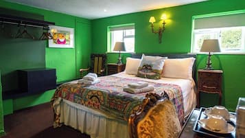 A green-themed bedroom with a bed, two bedside tables, a chair, and a wall-mounted TV.