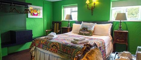 A green-themed bedroom with a bed, two bedside tables, a chair, and a wall-mounted TV.