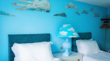A room with two beds, a nightstand with a lamp, and wall decorations.