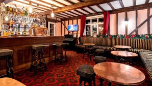 A bar area with stools, a piano, and a television. - The lion hotel  (Berriew)