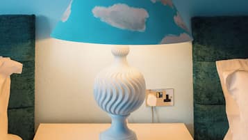Una habitación con una mesa blanca, una lámpara azul con diseños de nubes y una pared decorada con motivos de nubes.
