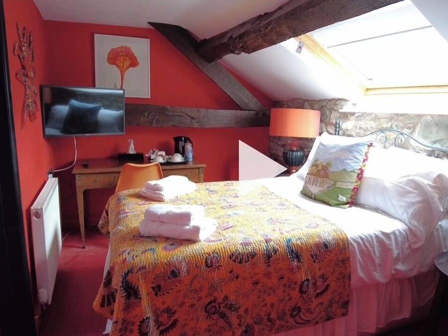 Un dormitorio con cama, escritorio, televisor y pared de piedra.