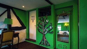 A room with a green wall, a tree mural, a bed, and a chair. - The lion hotel  (Berriew)