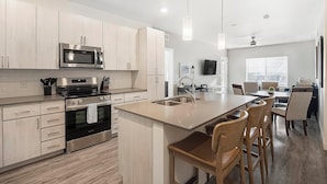 Een moderne keuken met roestvrijstalen apparatuur, een centraal eiland met barkrukken en een eetgedeelte met uitzicht.