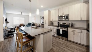 A modern kitchen with a central island, stainless steel appliances, and light wood cabinetry. - Landing | Amazing 1BD, Clubhouse, Pool (Mesa)