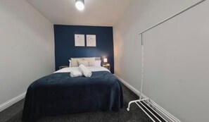 Ein Schlafzimmer mit einem Bett, einem Nachttisch und einer Wandleuchte.