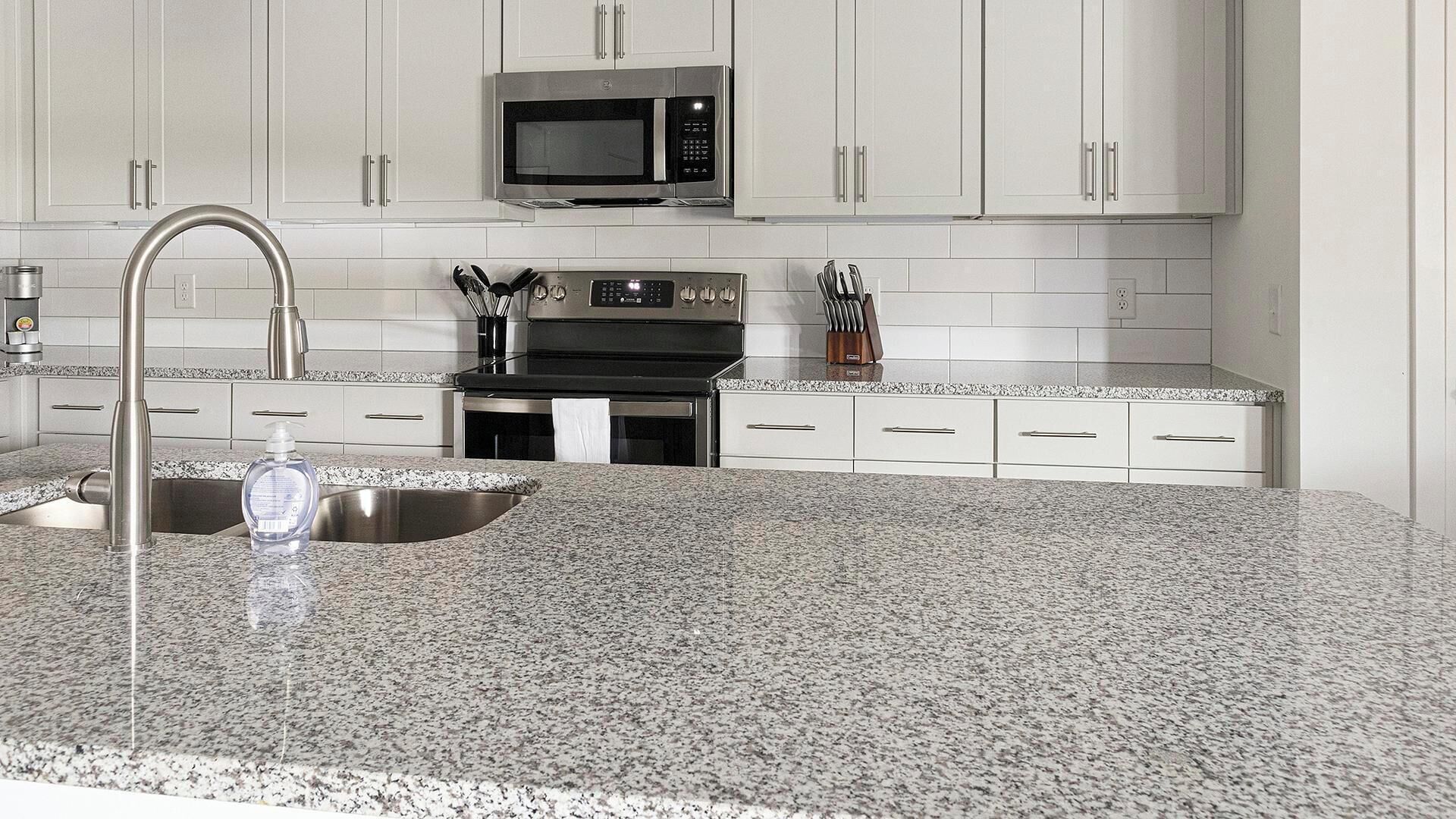 Una cucina moderna con piani in granito, elettrodomestici in acciaio inossidabile e mobili bianchi.