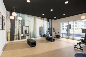 Ein geräumiges Zimmer mit großem Fenster, Wand-TV, Trainingsgeräten und Soundsystem.