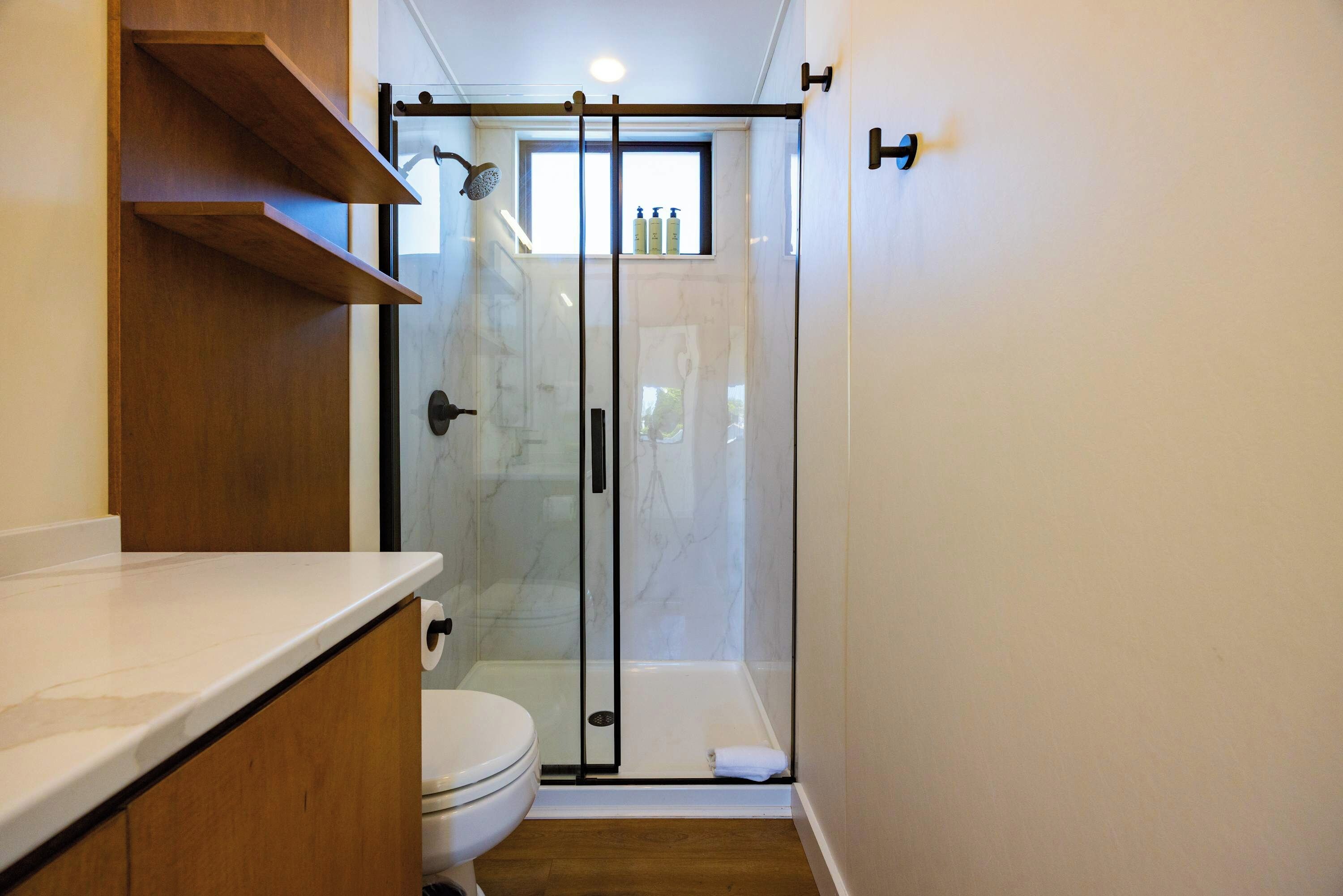 A bathroom with a toilet, a shower enclosure, and a wooden vanity.