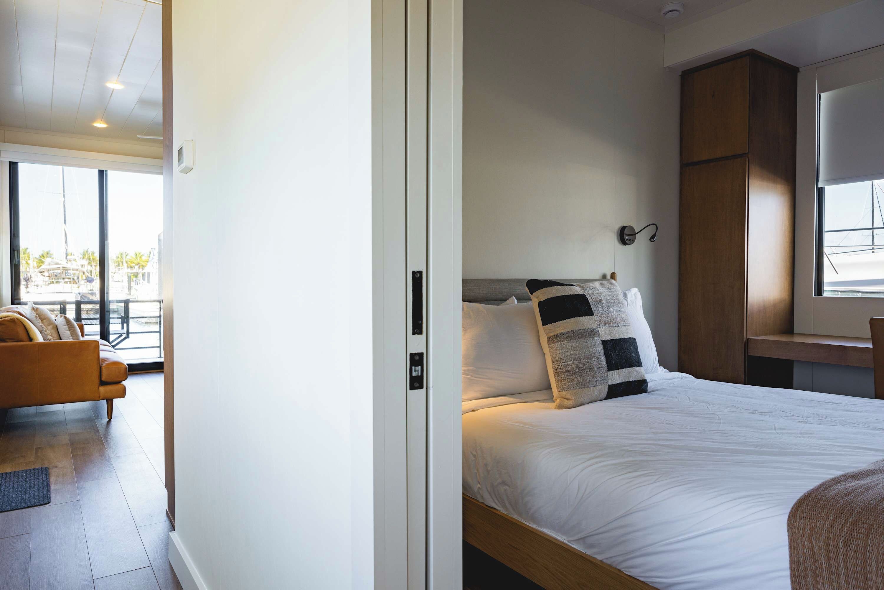 A bedroom with a bed, a nightstand, a window, and a view of the outside.
