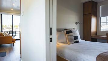 A bedroom with a bed, a nightstand, a window, and a view of the outside.