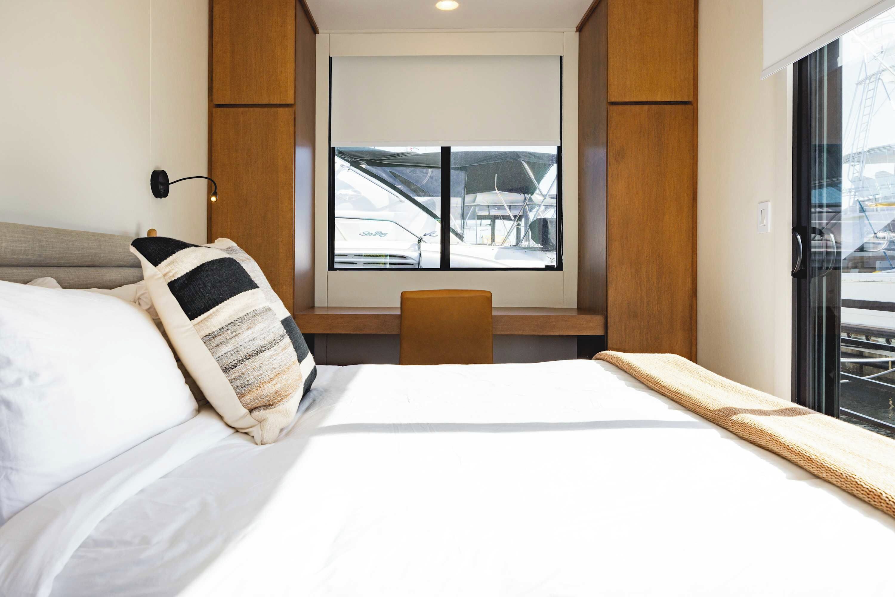 A hotel room with a bed, a desk, and a window with a view of a boat.
