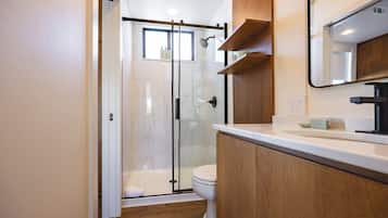 Une salle de bain moderne dotée d’une douche à parois de verre, de toilettes et d’un meuble-lavabo avec un miroir.