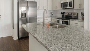 A modern kitchen with stainless steel appliances, granite countertops, and white cabinetry. - Landing | Spectacular 1BD, Gym, Clubhouse (Raleigh)