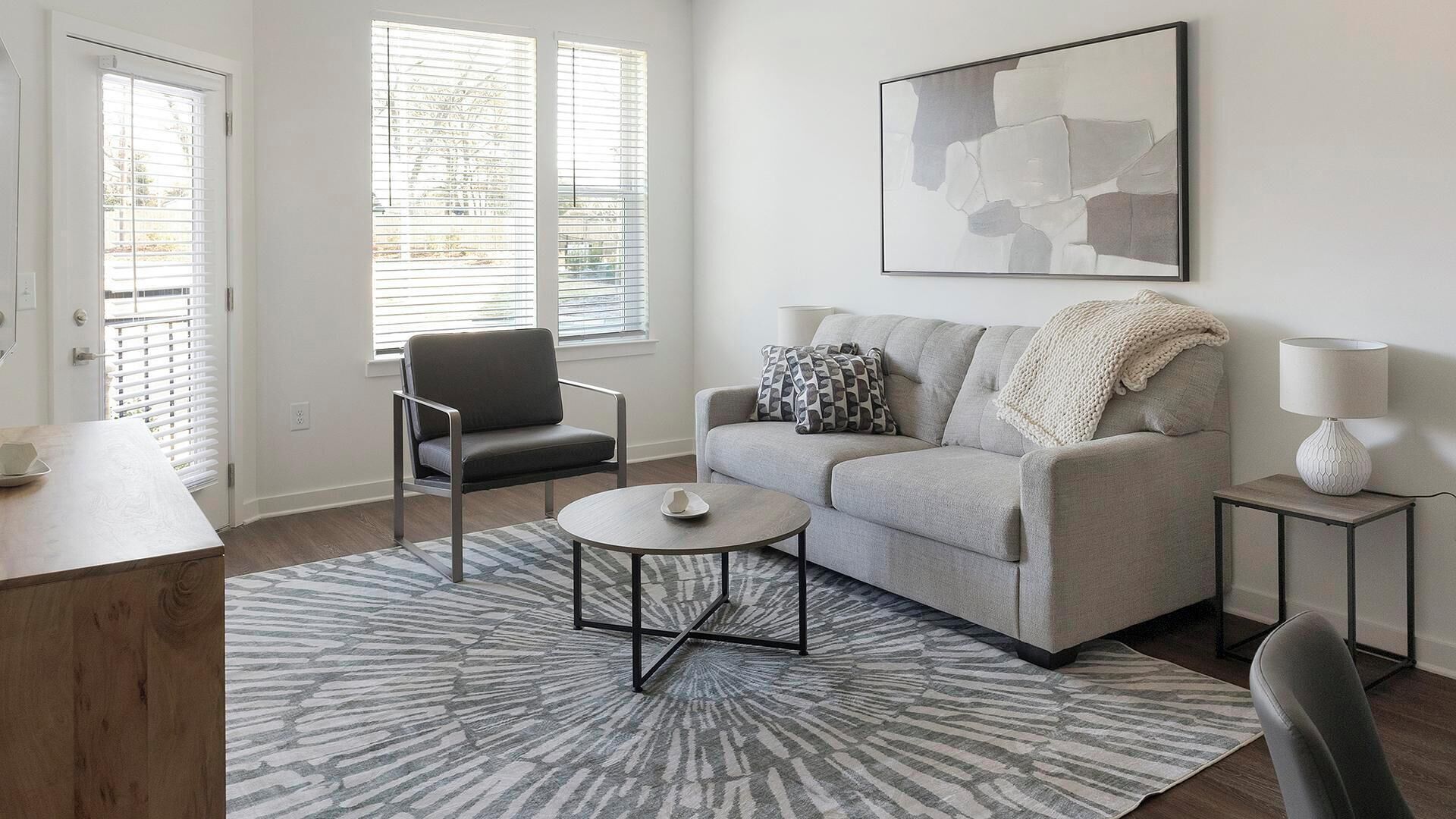 A modern living room with a sofa, a chair, a coffee table, a lamp, and a rug.