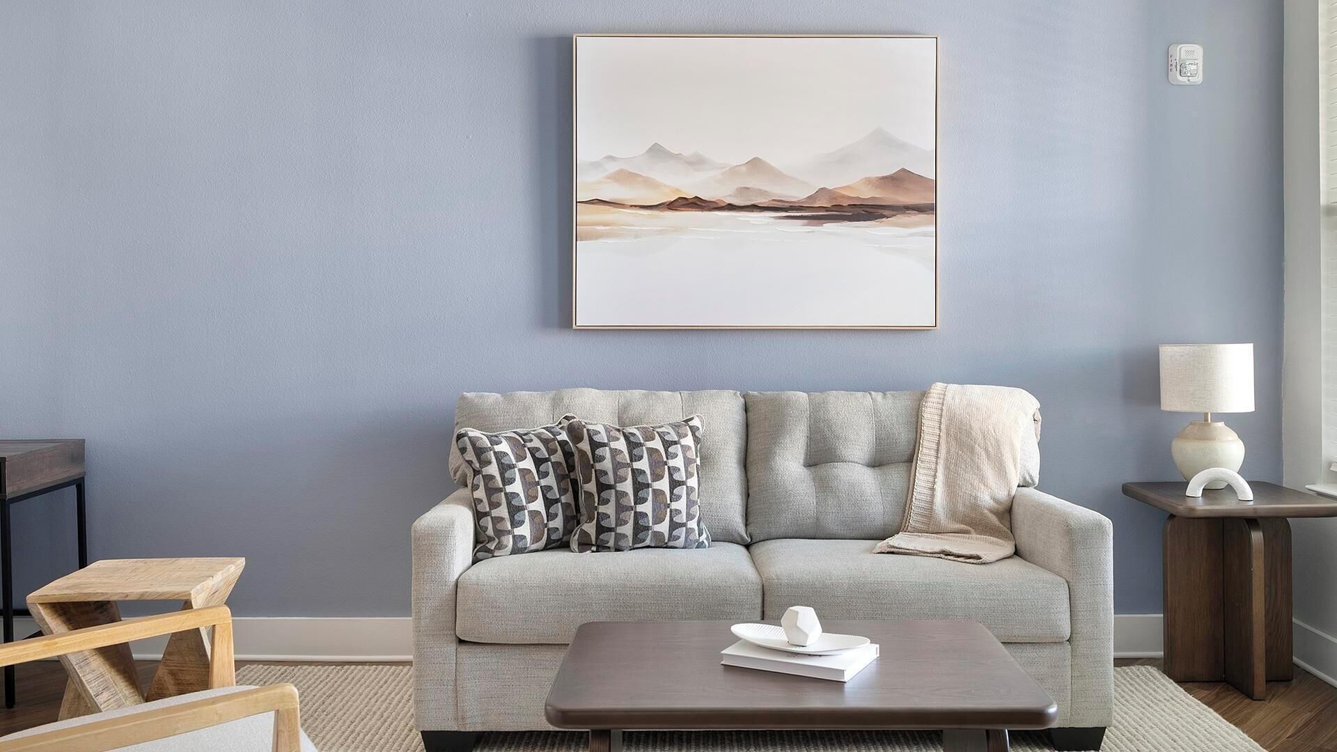 Ein Wohnzimmer mit einer Couch, Kissen, einem Couchtisch, einer Lampe und einem gerahmten Bild an der Wand.