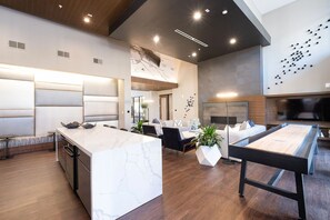 Una cocina moderna con encimera de mármol, armarios de madera y un comedor con mesa y sillas.