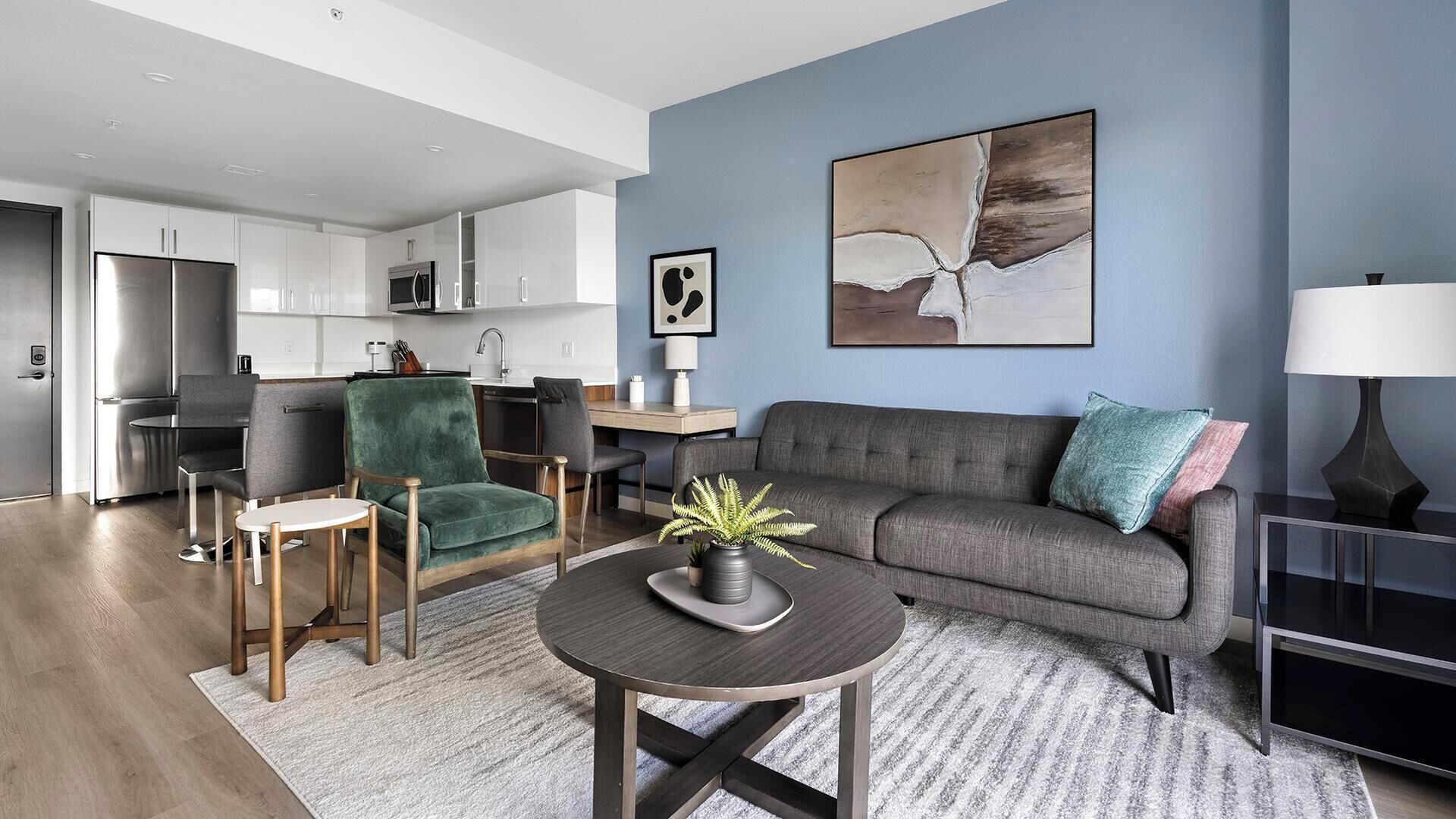 A modern living room with a grey sofa, a green armchair, and a round coffee table.