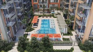 Een modern appartementencomplex met een centraal gelegen zwembad, balkons en weelderige begroeiing.