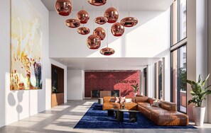 A spacious lobby with a leather sofa, a blue rug, and a red brick wall with 'CENTRO CITY' signage. - Landing | Incredible 1BD, Yoga Studio, Game Room (Miami)