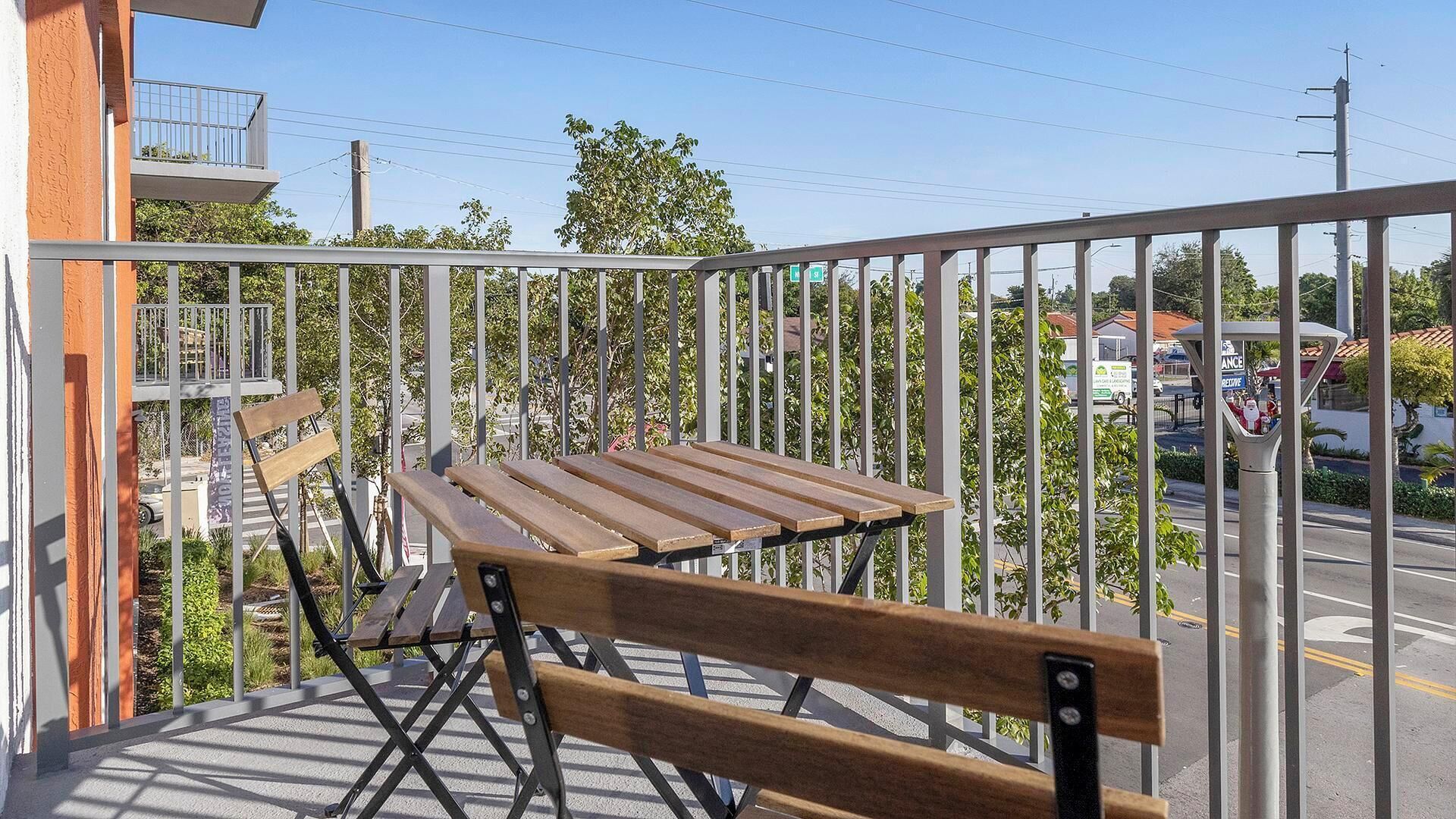 Un balcon avec un banc en bois et une rambarde en métal.
