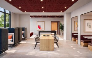 Een moderne vergaderruimte met een houten tafel, zwarte stoelen en een rood plafond.