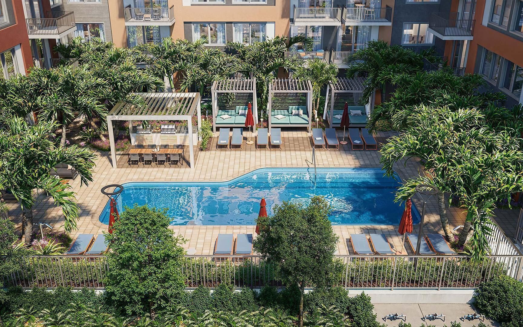 Una piscina sul tetto con poltrona a sdraio e lettini, immersa nel verde e affiancata da un edificio a più piani.