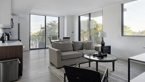 Ein modernes Wohnzimmer mit Sofa, Couchtisch, Schreibtisch und einem Balkon mit Blick.