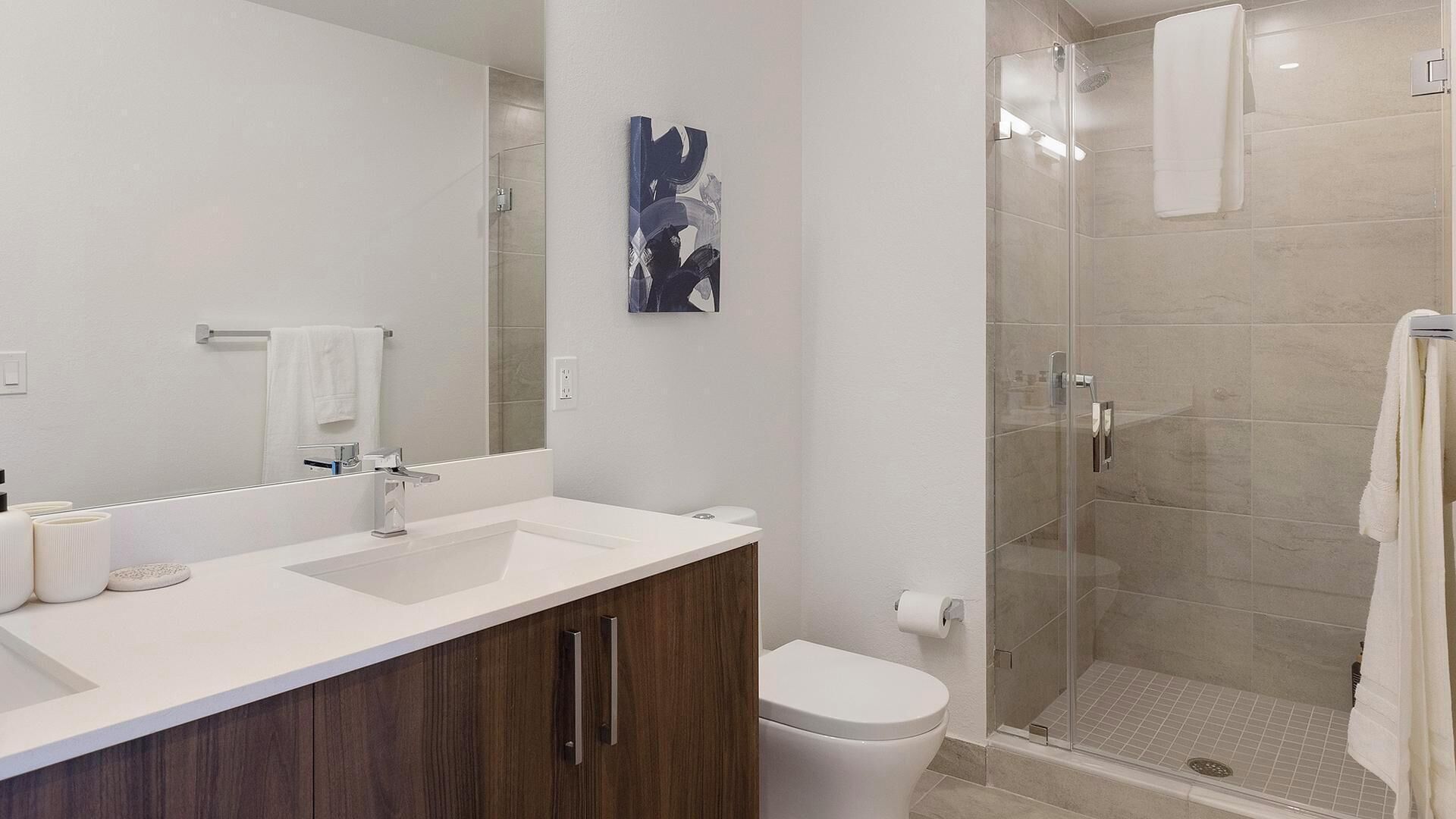 A modern bathroom with a shower, toilet, and sink.