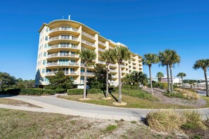 A multi-story hotel with balconies, palm trees, and a clear blue sky. - The Indies 609 (Gulf Shores)