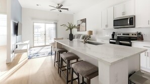 A modern kitchen with a large island, white cabinetry, and a built-in microwave. - Landing | Beautiful 2BD, Pool (Casas Adobes)