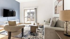 A modern living room with a flat-screen TV, a sofa, a coffee table, and a glass lamp. - Landing | Beautiful 2BD, Pool (Casas Adobes)
