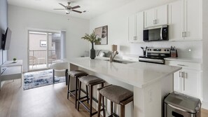 A modern kitchen with a large island, bar stools, a microwave, and a stove. - Landing | Beautiful 2BD, Pool (Casas Adobes)