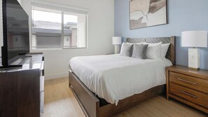 A bedroom with a bed, bedside tables, a TV, and a window. - Landing | Incredible 2BD, Pool (Casas Adobes)