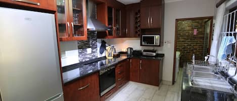 A kitchen with wooden cabinets, a stainless steel refrigerator, a microwave, and a dishwasher.