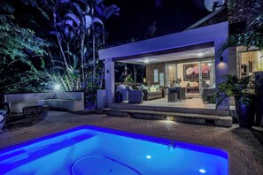 A modern outdoor pool area with a patio, seating, and a well-lit interior space. - Pelican's Nest St Lucia Private Holiday House (St. Lucia)