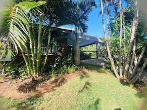 A modern building with a brick facade, surrounded by lush greenery and palm trees.