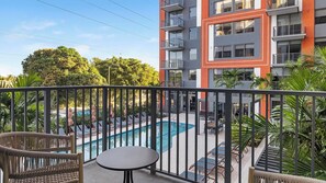 A balcony with a pool, wicker chairs, and a table. - Landing | Beautiful Studio, Game Room, Yoga Studio (Miami)