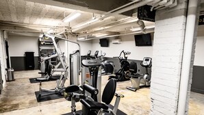 Ein Fitnessstudio mit verschiedenen Trainingsgeräten, darunter eine Beinpresse, eine Brustpresse und ein Ergometer.